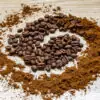 A swirl of coffee beans and ground coffee on a wood surface showing All You Need to Know About Whole Bean vs Ground Coffee