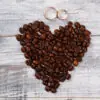 wedding rings on a board above coffee beans in shape of heart to hint at great coffee bridal party gifts