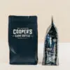 cooper's cask coffee bags on a white table with a beige background showing retailers how cooper's works as wholesale coffee suppliers