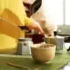 closeup of woman in kitchen showing how to make an espresso using a moka pot